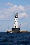Isle Royale National Park | Rock of Ages Lighthouse | The Rock of Ages reef consists of outcroppings of rocks west of Isle Royale that is a hazard to navigation. Several wrecks occurred on the reef prior to the construction of the lighthouse. In 1908, construction began on the lighthouse. The construction crew established a base at Washington Harbor and used the lighthouse tender Amaranth to ferry men and materials to the site. A section of a rock was blasted to provide a flat area for the foundation. A steel cylindrical wall was erected and filled with concrete to give a pier that was 50 ft (15 m) in diameter and 25 ft (7.6 m) tall. The skeleton of the tower was built from steel. The inner and outer walls of the tower were constructed of brick. The concrete floors were supported on radial steel beams. The spiral stairs were cast iron. When the tower was enclosed, a bunkhouse, mess hall, and galley were built on a timber platform on the rock. The lighthouse was lit in 1908 with a temporary light. | Photo: James McKay, Scuba Center